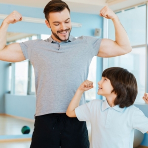 Dad and son smiling and flexing their arms